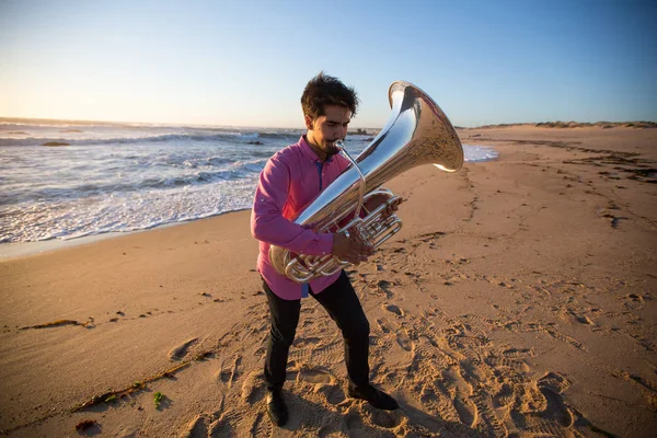 Wind instrument musician plays on the ocean coast.