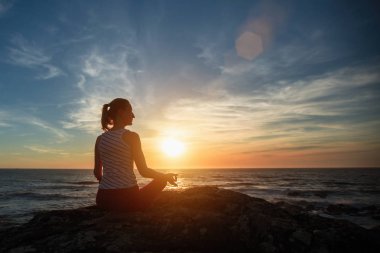 Yoga meditasyon kadın silueti şaşırtıcı günbatımı sırasında denizde.