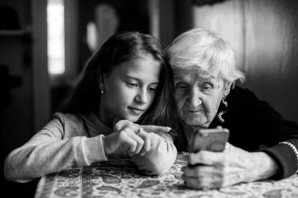 Linda Niña Muestra Bisabuela Teléfono Inteligente Foto Blanco Negro — Foto de Stock