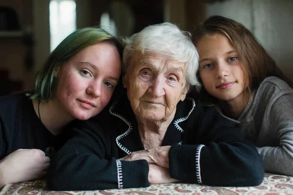 Old lady granny with two lovely girls great-granddaughters. Family portrait.