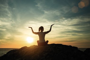 Yoga silueti genç kadın inanılmaz gün batımında deniz kıyısında pratik. 