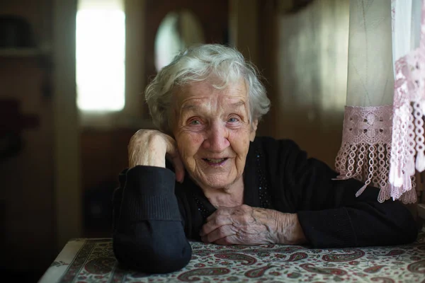一个快乐的老妇人坐在房子里的桌子旁的肖像 — 图库照片