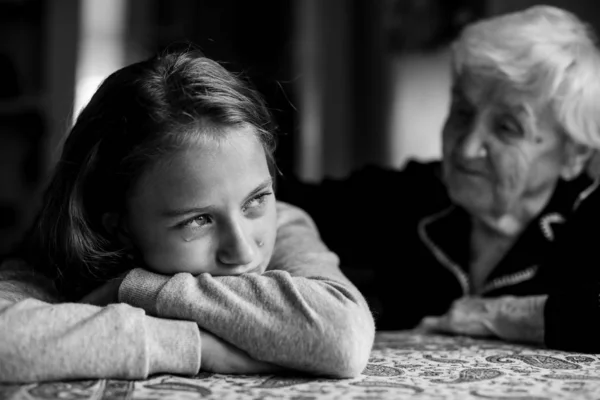 A crying little girl is comforted by her grandmother. Black and white photo.