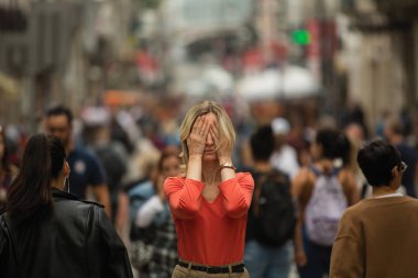 Üzgün depresif kadın kalabalık sokakta yürüyen insanlarla çevrili elleri ile gözlerini kapatır. Halka açık yerlerde panik atak. 