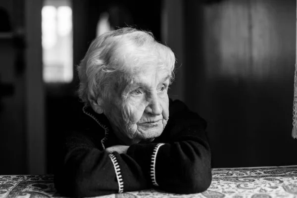 孤独的老妇人的肖像坐在桌子旁 黑白照片 — 图库照片