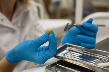 Diş kliniğinde sarı diş ve diş aletleri tutan Eller diş hekimi. 