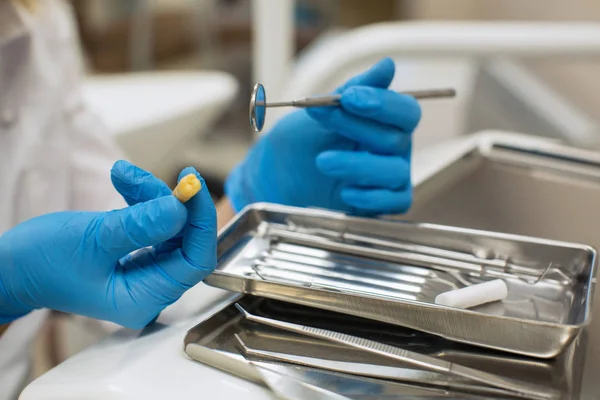 Dentist\'s hands holding yellow tooth and dental tools in dental clinic. Medicine, stomatology and healthcare concept.