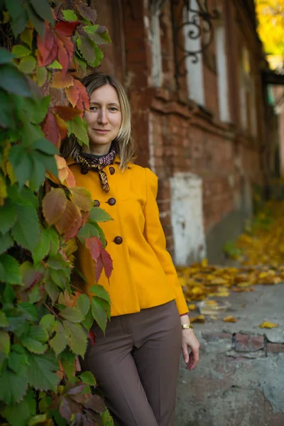Блондинка позує на осінній вулиці з жовтим листям . — стокове фото