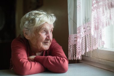 Pencerenin yanında yaşlı bir kadının portresi var.