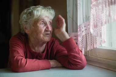 Duygusal yaşlı kadın mutfak masasında oturuyor..