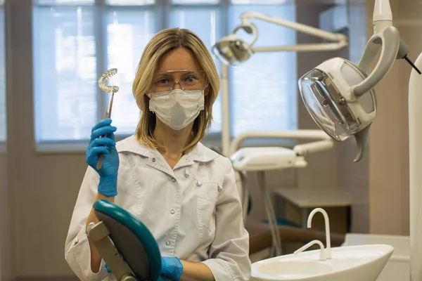 女性歯科医は 歯科事務所で取り外し可能な歯のアライメントと補正トレーナーアプライアンスを示しています — ストック写真
