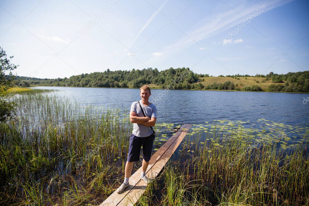 Young man on the river with a wooden boards in the summer in the village.