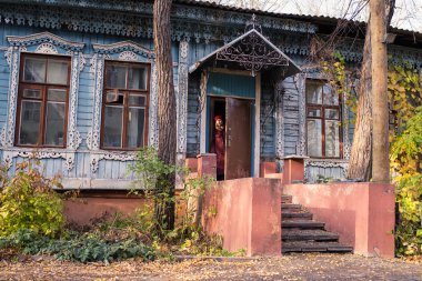 Genç bir kadın eski bir kır evinin verandasında duruyor.. 