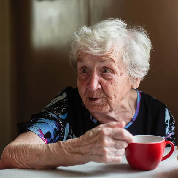 一位老年妇女养恤金领取者坐在自家厨房里吃早餐 — 图库照片