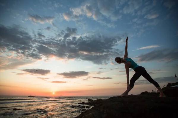 海岸で日没時にヨガを練習している若い女性 — ストック写真