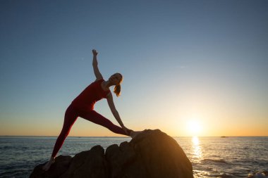 İnanılmaz gün batımında deniz sahilinde yoga yapan bir kadın.. 