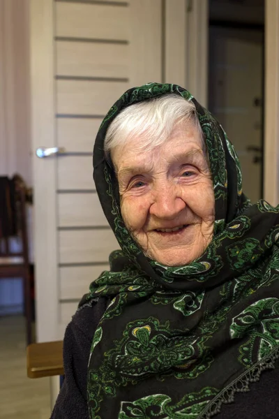 Portrait of an old russian woman with a scarf on her head.