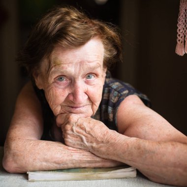 Emekli Rus kadın evde bir masada oturuyor, portresi var..