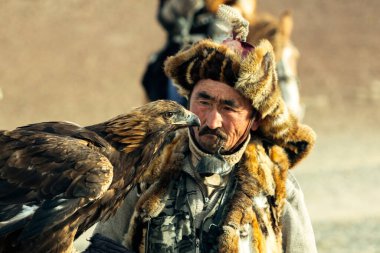 BAYAN-OLGII, MONGOLIA - SEP 28, 2017: Berkutchi (Kazak Kartal Avcısı) Bayan-Olgii aimag dağlarında kollarında altın kartallarla avlanırken.