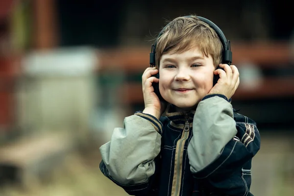 一个戴着耳机的有趣的小男孩 在户外 — 图库照片