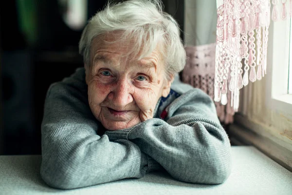 Yaşlı Bir Kadın Gülümseyen Bir Portre Kameraya Bakıyor Mutfakta Oturuyor — Stok fotoğraf