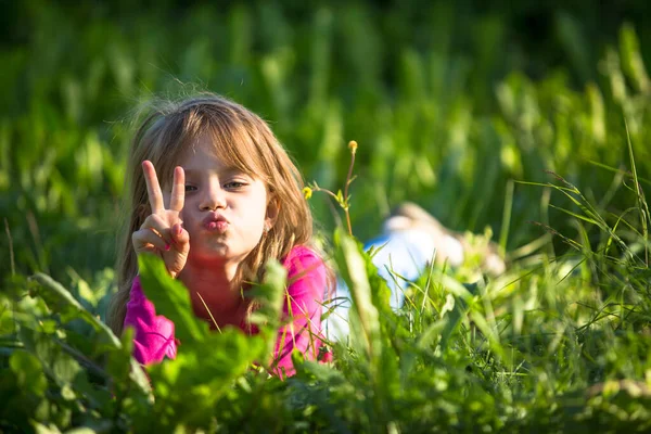 一个可爱的小女孩躺在草地上的绿草里 — 图库照片