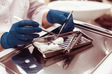 Diş hekiminin elleri tıbbi geçmişinde diş aletlerini tutuyor.. 