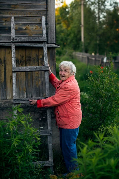 Old Woman Stands Her Village House Holding Wooden Staircase — Stock Photo, Image