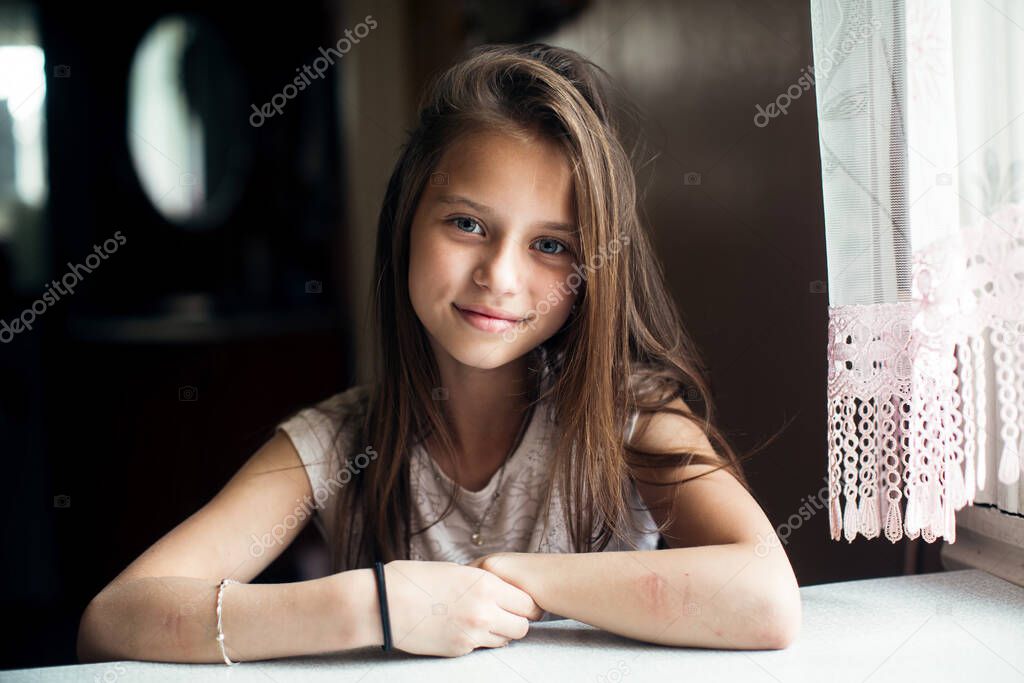 Portrait of cute little girl sitting at the table.