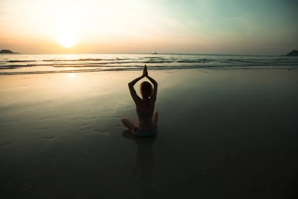 日落时在海滩上练习瑜伽的年轻女子 — 图库照片