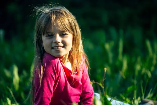 一个微笑的可爱小女孩躺在绿绿的草地上的画像 — 图库照片