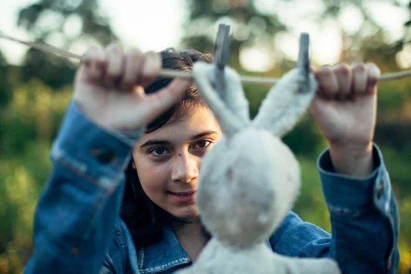 소녀가 빨랫줄에 장난감 토끼를 말린다 — 스톡 사진