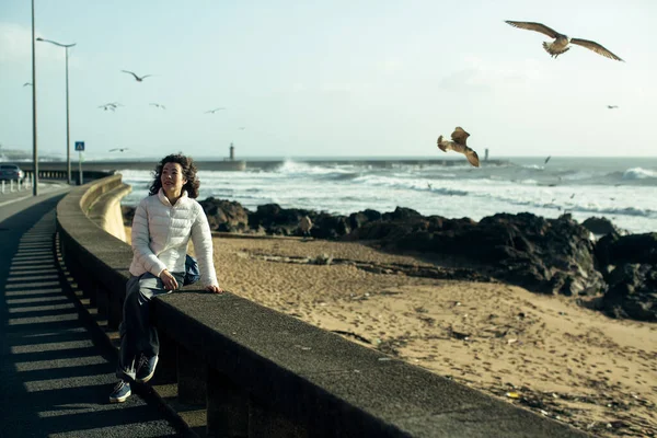 Giovane Donna Multiculturale Seduta Sul Lungomare Gabbiani Sorvolano Surf Schiumoso — Foto Stock