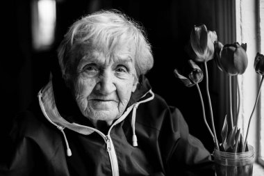 Kameraya poz veren yaşlı bir kadının portresi. Siyah beyaz fotoğraf.