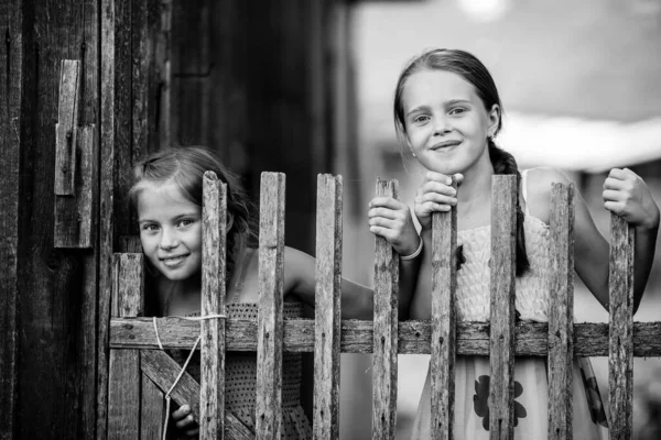 Két Kislány Pózol Egy Rusztikus Fából Készült Kerítés Mellett Fekete — Stock Fotó