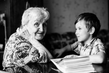 Kitaplı yaşlı kadın ve genç torun. Siyah beyaz fotoğraf..
