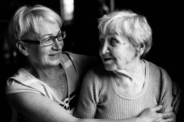 Happy old woman with her adult daughter. Black and white photo.