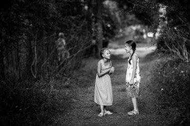 Çam ormanında iki küçük kız. Siyah beyaz fotoğraf.