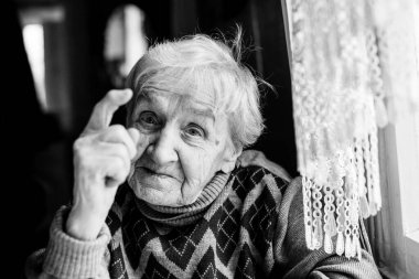 Yaşlı bir kadının portresi öfkeyle parmağını sallıyor. Siyah beyaz fotoğraf..