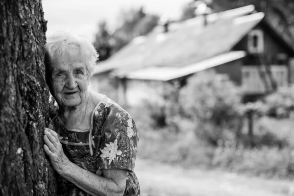 老人は田舎の家の近くで木を抱いていた 白黒写真 — ストック写真