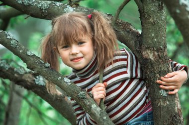 Bahçedeki ağaçta oturan küçük bir kızın portresi..