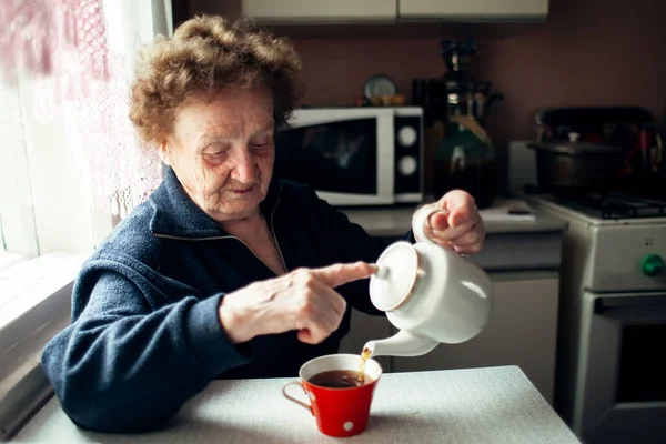 一个老妇人在厨房喝茶 — 图库照片