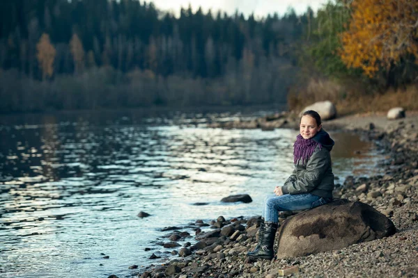 Genç Bir Kız Nehir Kıyısındaki Bir Kayanın Üzerinde Oturuyor — Stok fotoğraf