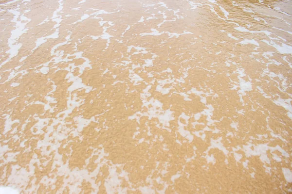 Espuma branca na areia da praia — Fotografia de Stock