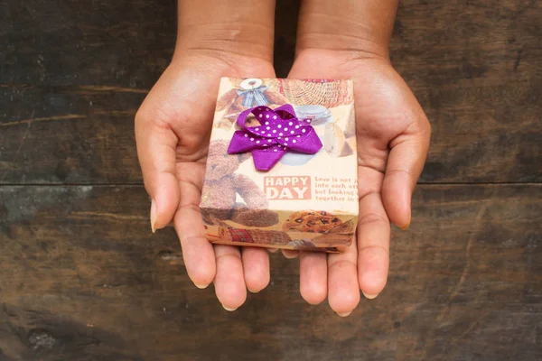 Asyalı Kız Tutun Siyah Ahşap Arka Plan ile Kahverengi Hediye Kutusu Tutun