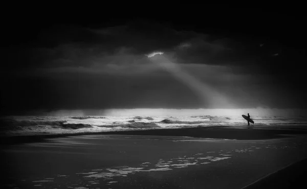 Bir fırtınalı gün içinde bir ışık demeti aydınlatan uygulamaya koymak için konsantre sörfçü