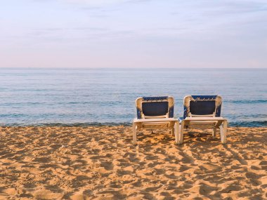 Sahilde şezlong yanında sahile denize bakan güneş