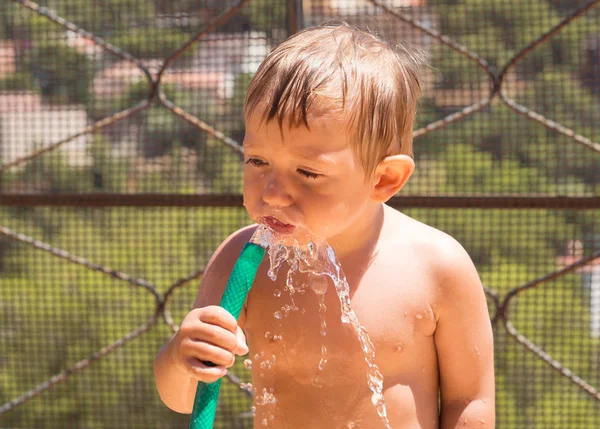 Oynama ve bir hortum ile su ile sıcaktan serinlemek çocuk
