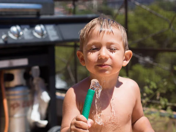 Oynama ve bir hortum ile su ile sıcaktan serinlemek çocuk