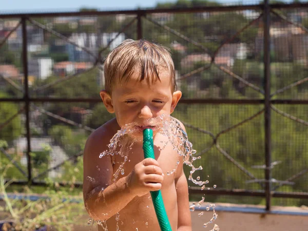 Child playing and cooling off from the heat with water and with a hose